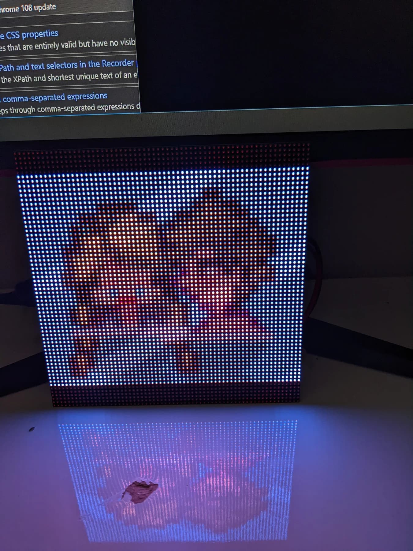 Unframed LED matrix displaying pixel art beneath a monitor