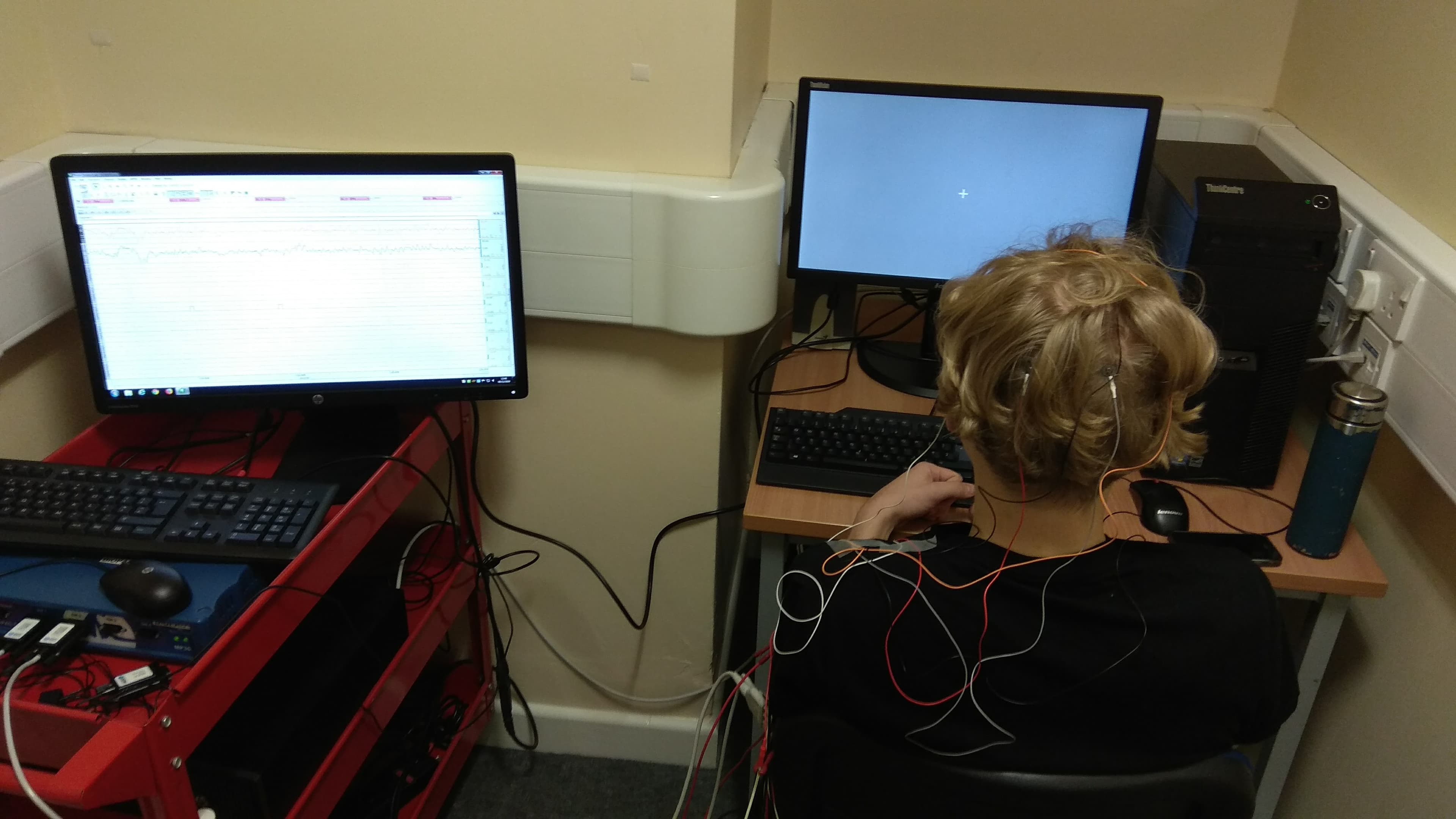 Participant wearing EEG electrodes during the visual attention experiment, with the recording and task computers beside them